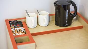 Un safata de fusta amb dues tasses blanques, una cafetera negra i una caixa de càpsules de cafè Aurora.