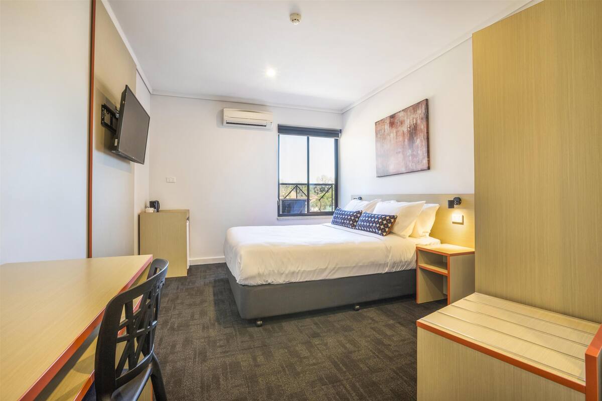 Ein modernes Hotelzimmer mit Bett, Nachttischen, Schreibtisch und Stuhl.