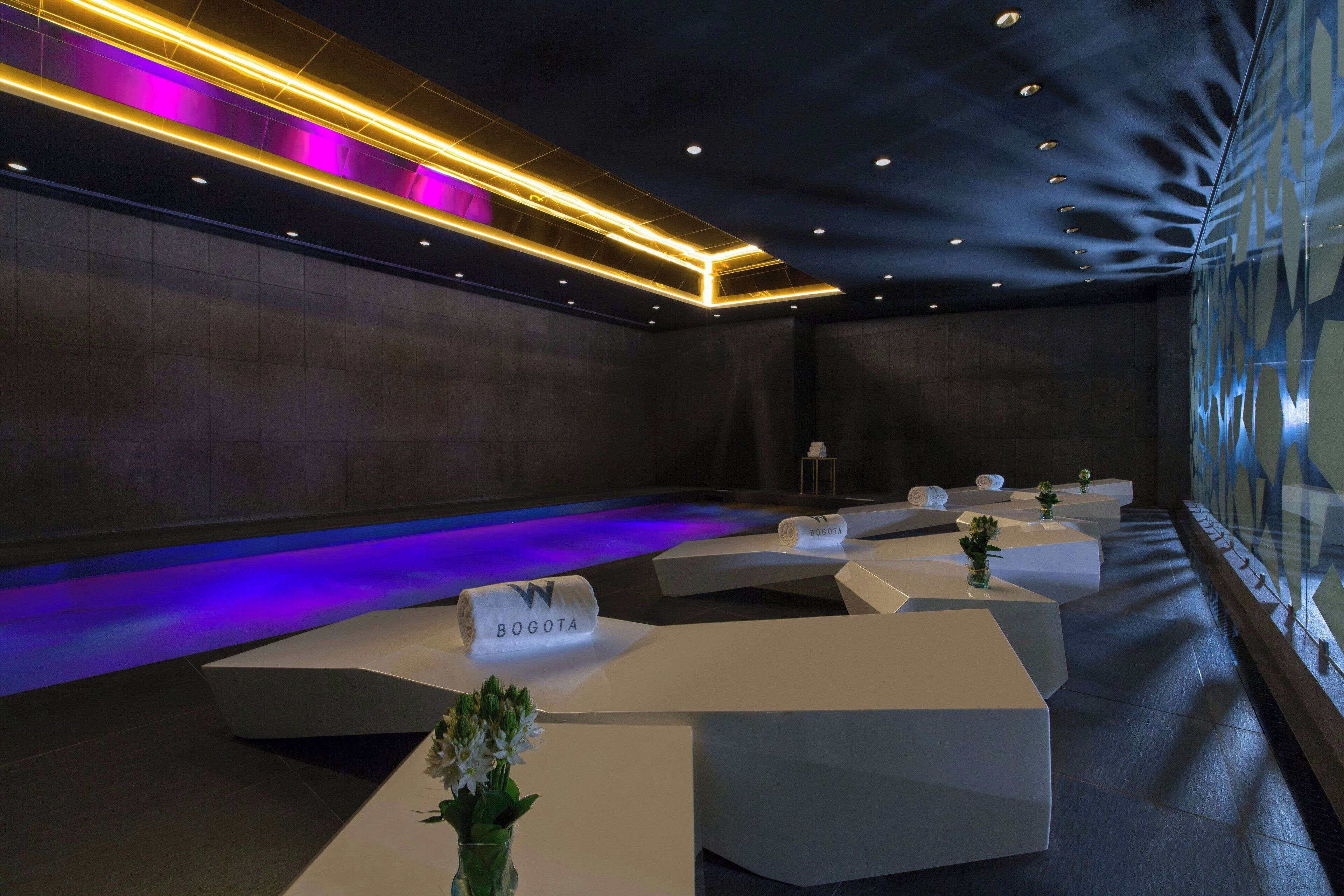 A modern conference room with white tables, a glass partition, and a ceiling with recessed lighting.
