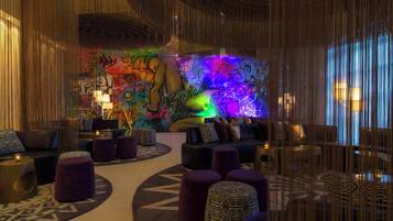 A modern lounge area with a colorful graffiti wall, plush seating, and ambient lighting.
