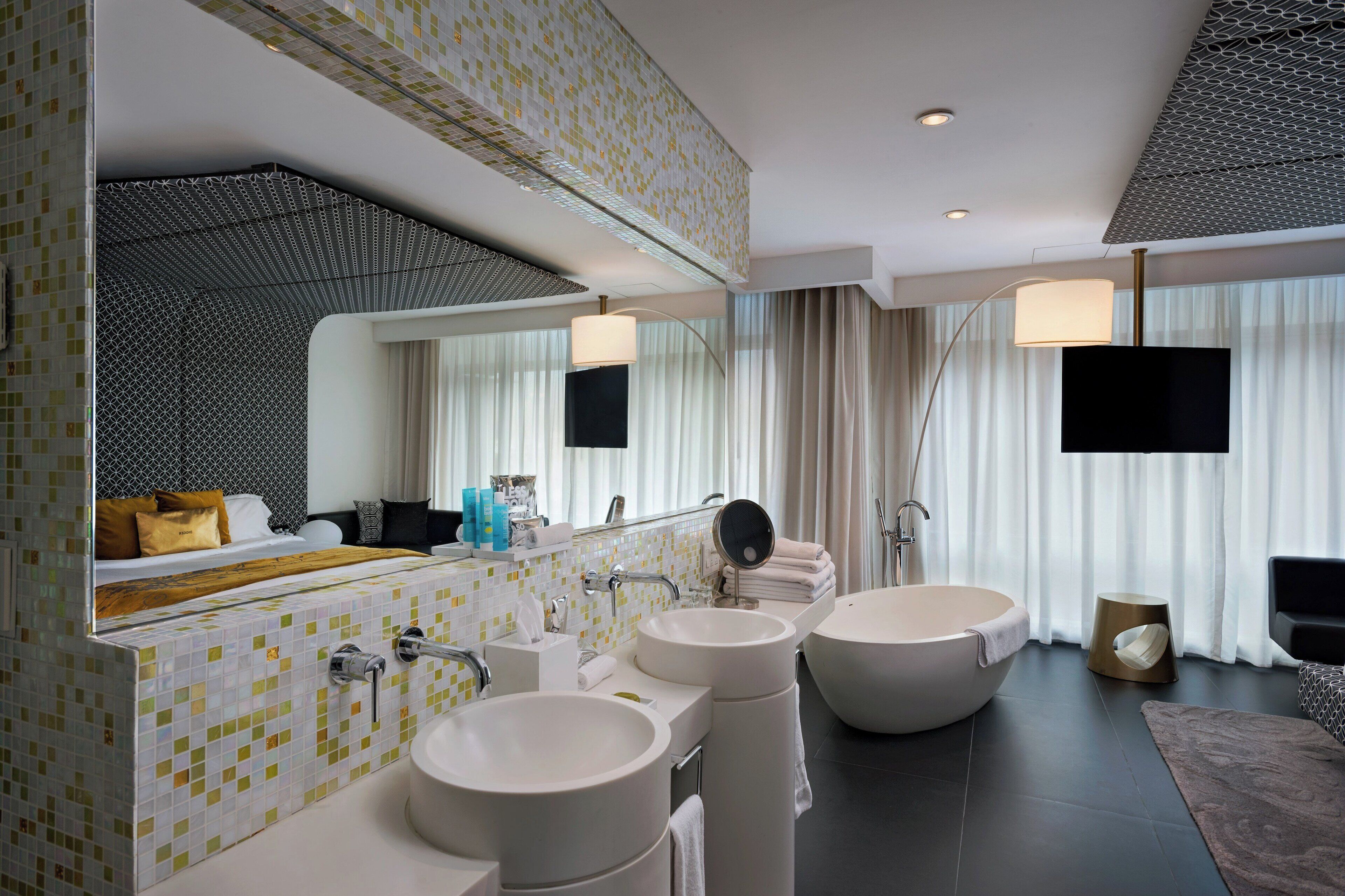 Un baño moderno con tres lavamanos grandes, una bañera y un espejo amplio.