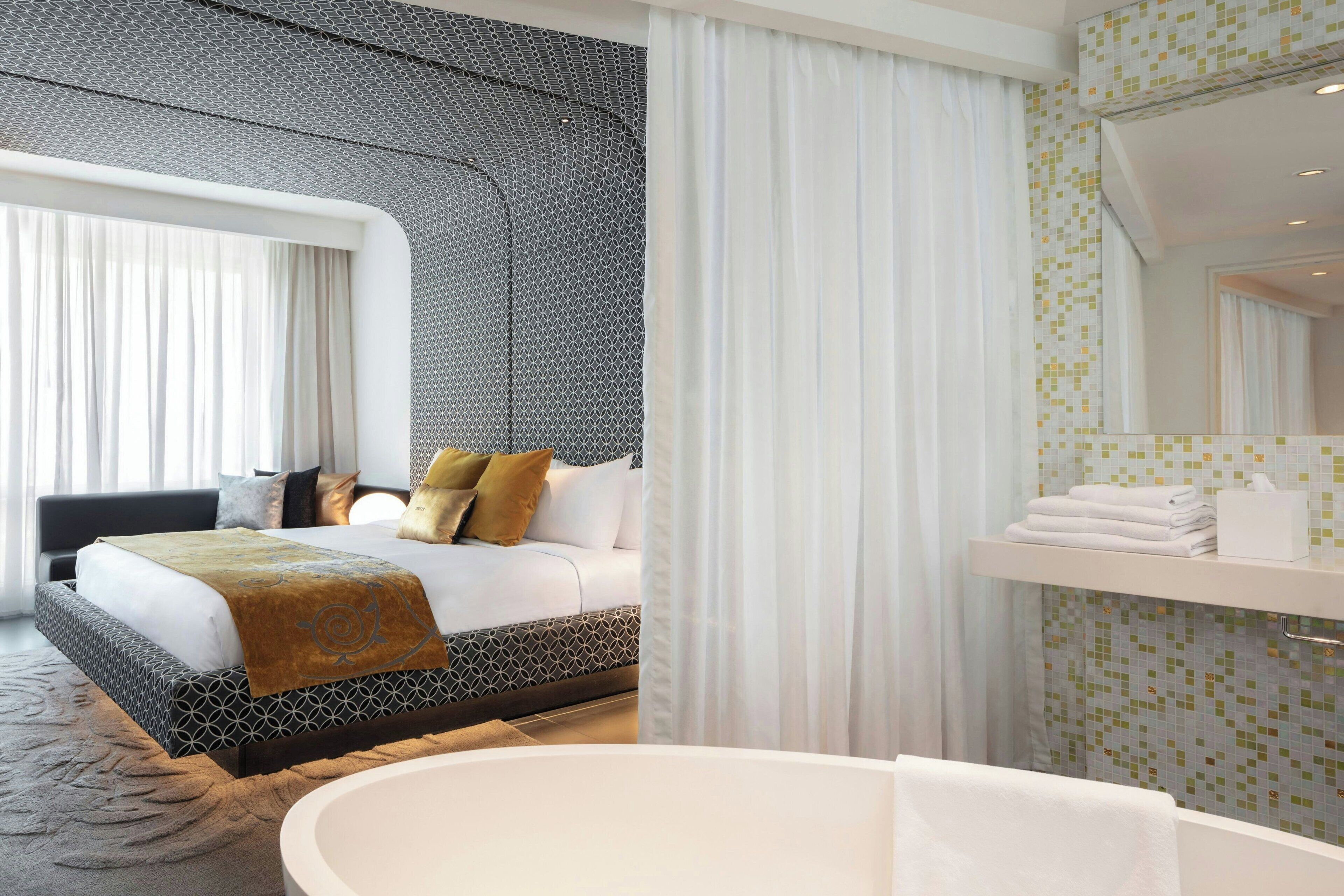 Ein modernes Hotelzimmer mit einem großen Bett, einem separaten Badezimmer und Blick auf die Stadt.