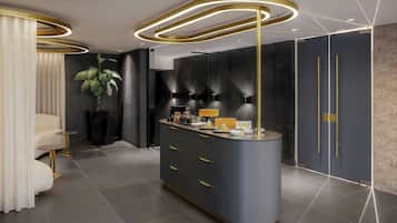 Un hall d’hôtel moderne avec un comptoir d’accueil incurvé, une plante en pot et un espace salon agrémenté d’un canapé blanc et de touches dorées.