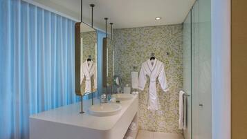 Un baño moderno con un espejo grande, dos lavamanos y una cabina de ducha de vidrio.
