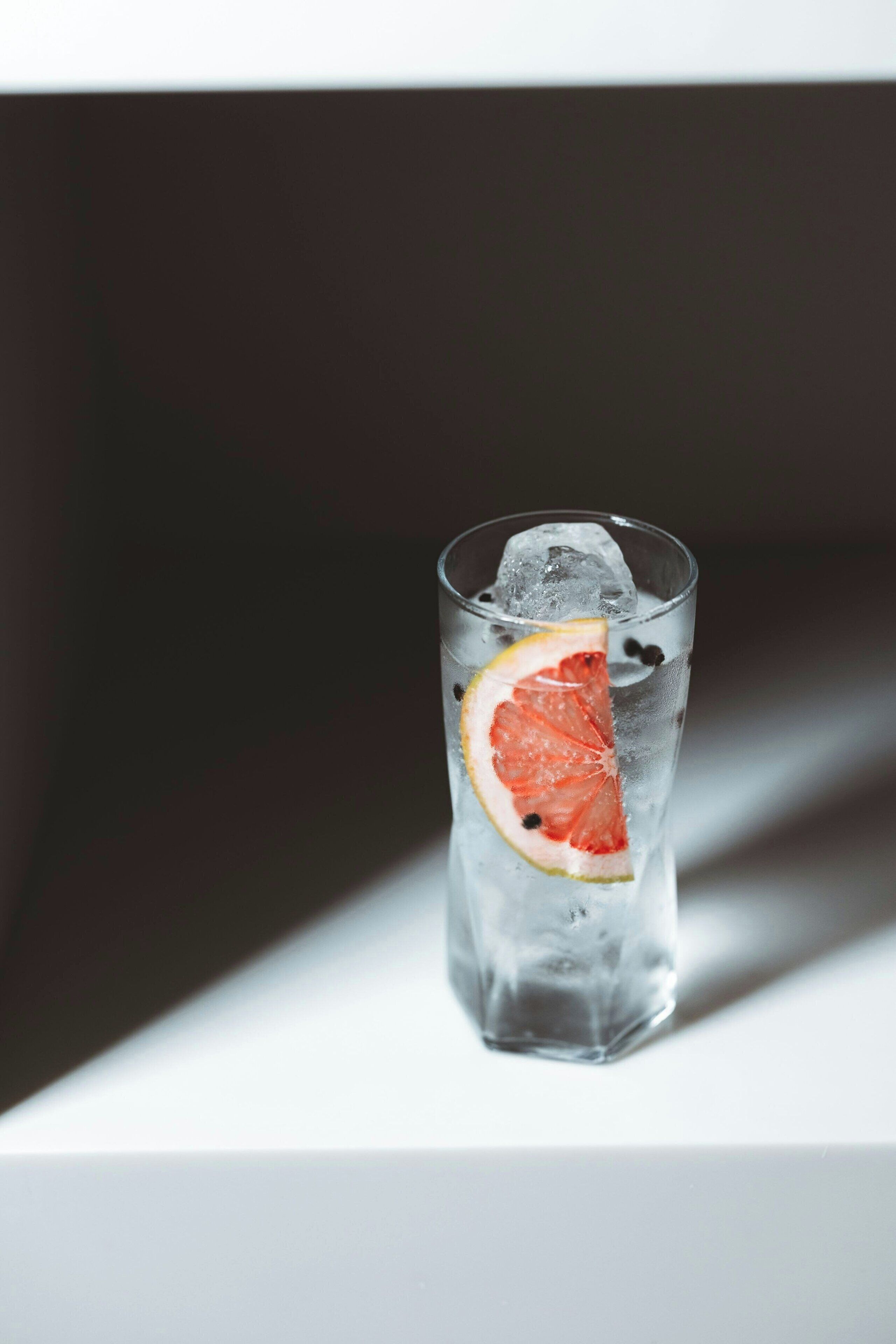Un verre contenant une tranche de pamplemousse et des glaçons.