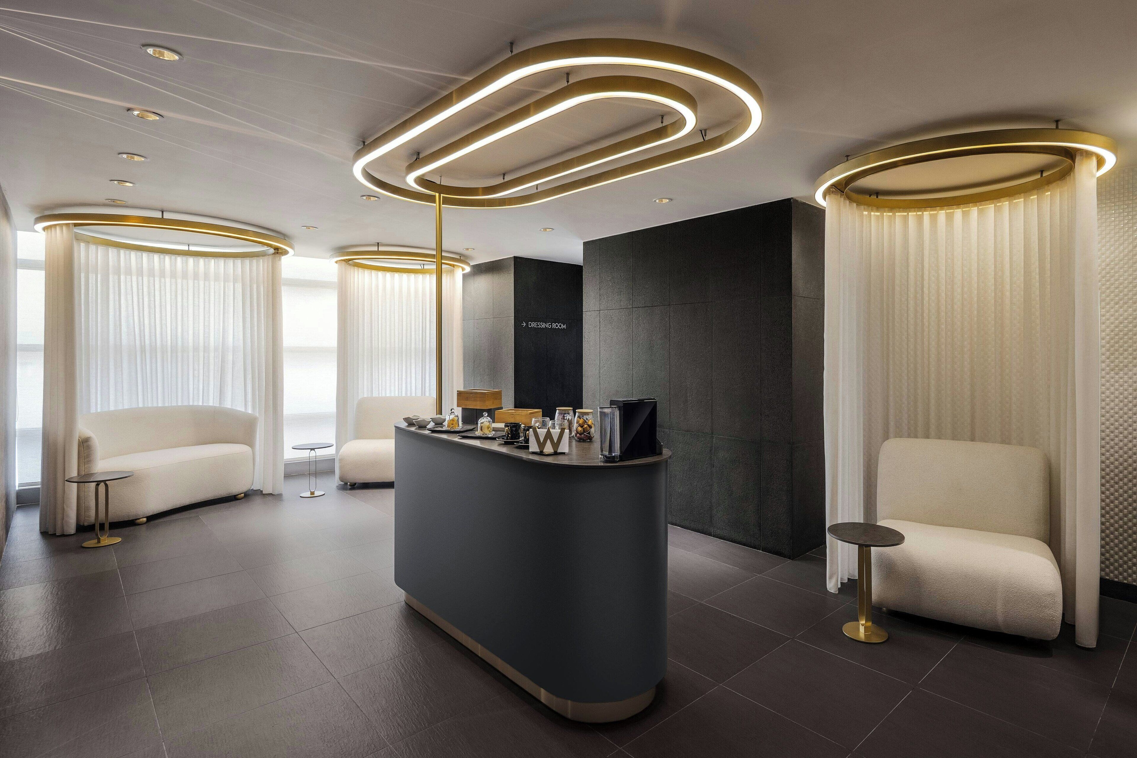 Un espace d’accueil moderne comprenant un comptoir central, deux canapés et une colonne décorative dotée d’un éclairage.