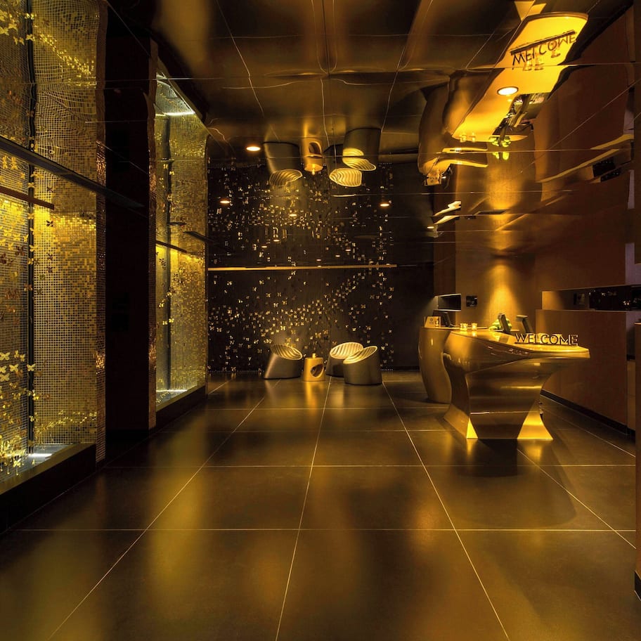 A modern interior with a glass wall displaying butterflies, a reception area with a 'Welcome' sign, and a sleek, metallic reception desk.