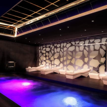 A modern spa with a heated floor, reclining chairs, and a geometric wall design.