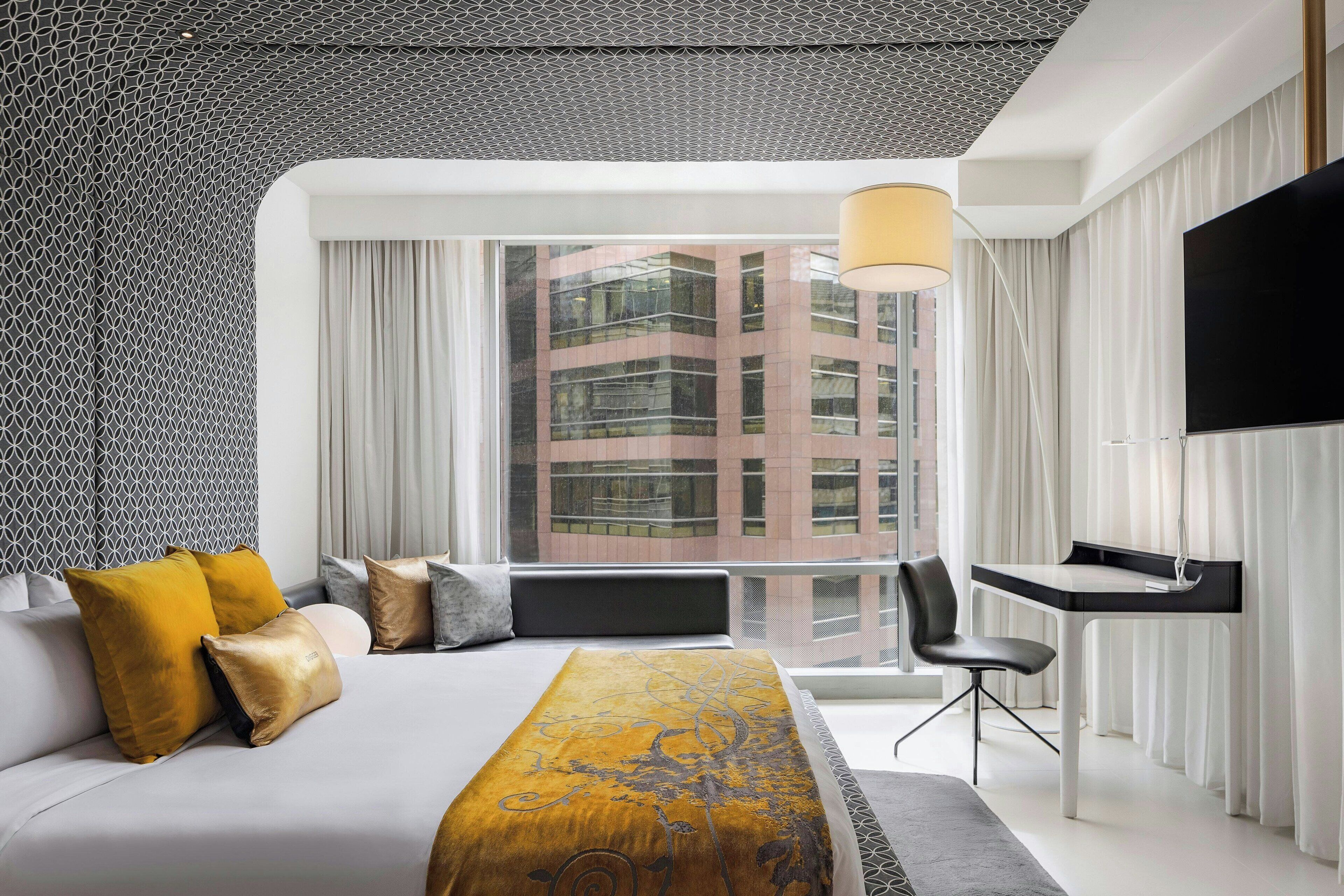 Una habitación de hotel moderna con una cama grande, un escritorio y una televisión.