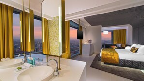 A modern hotel room with a large bed, a separate bathroom with a double sink, and a city view. - W Bogota (Bogotá)