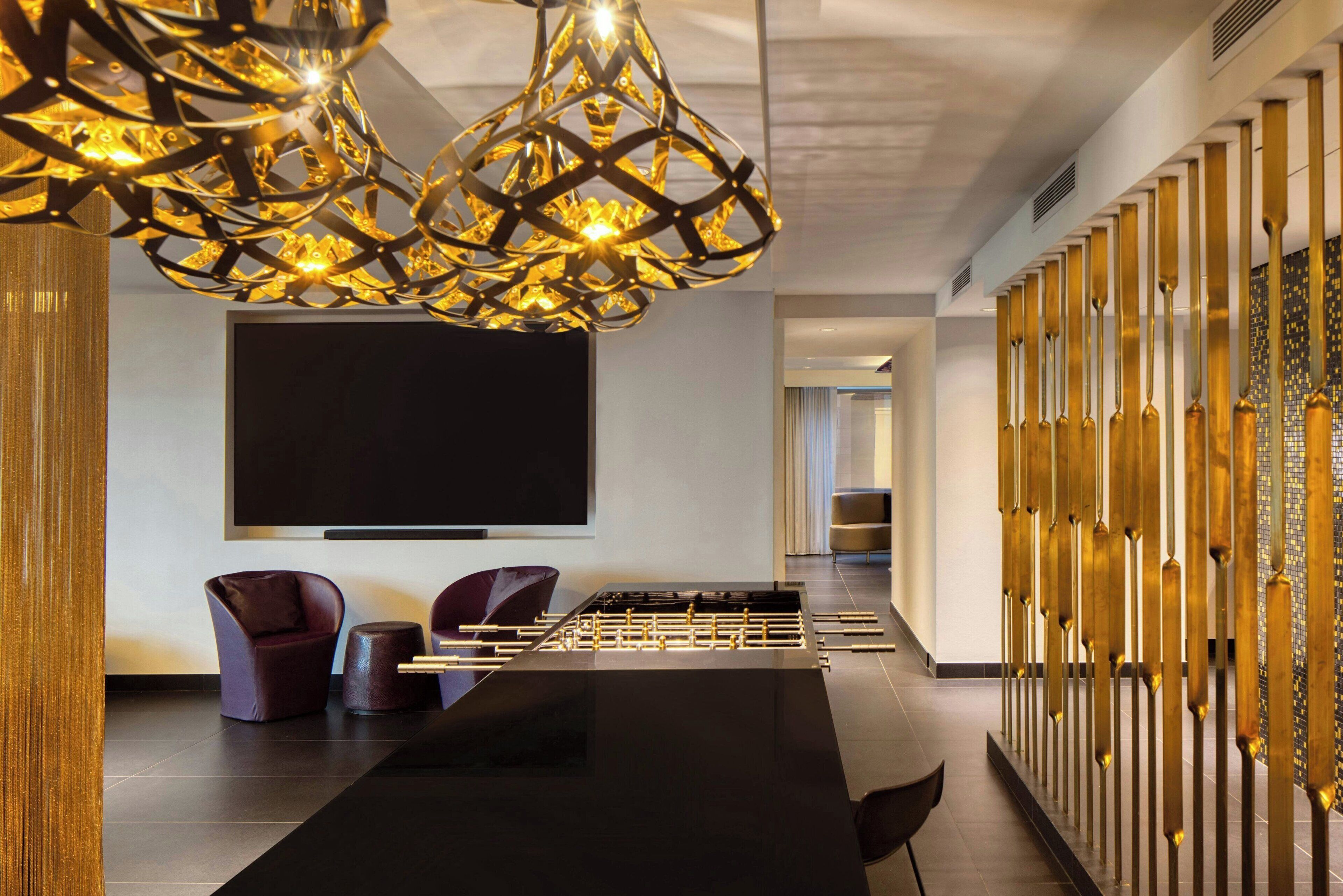 A modern room with a foosball table, comfortable seating, and a large flat-screen TV.