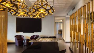 A modern room with a foosball table, comfortable seating, and a large flat-screen TV.