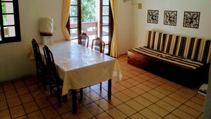A dining area with a table and chairs, a sofa, and a window with curtains. - Ingleses Residence (Florianópolis)