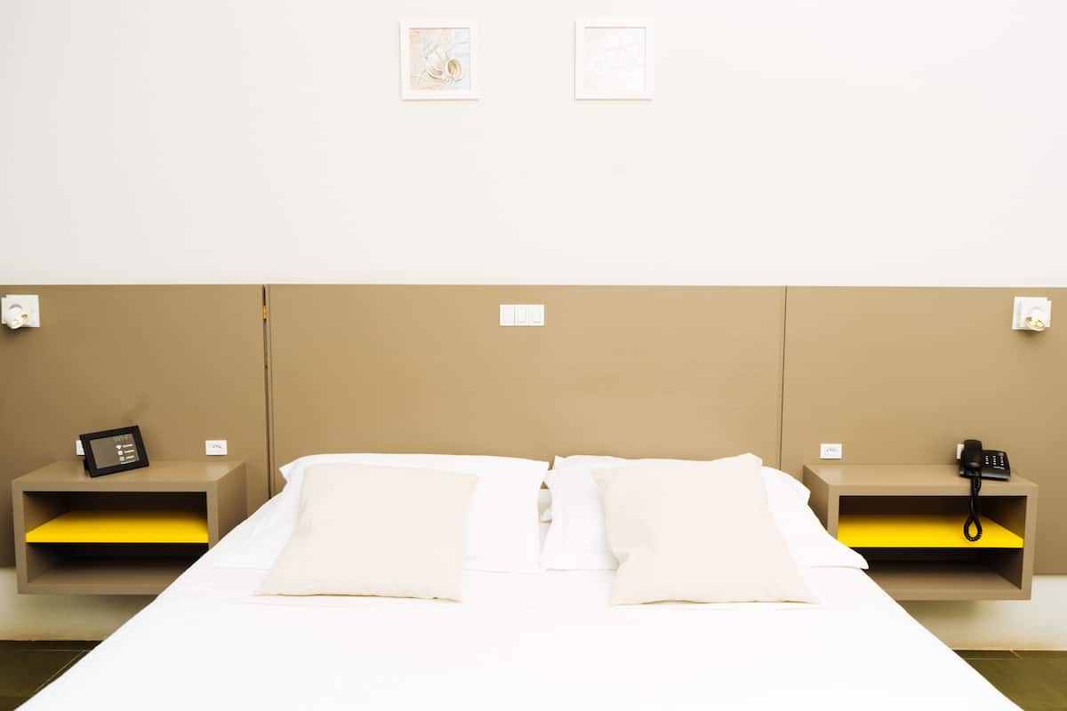 A hotel room with a bed, two bedside tables, and a headboard.