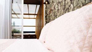Una camera da letto con un letto, una finestra e una parete decorata con un motivo a foglia.