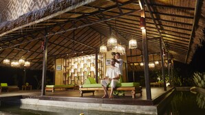 A covered outdoor seating area with benches and a pool. - Wareerak Hot Spring & Wellness (Khlong Thom)