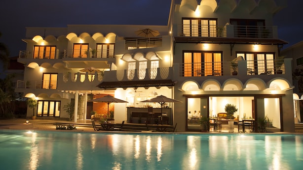 Un hôtel à plusieurs étages doté d’une piscine, d’un espace extérieur aménagé et de nombreux balcons.