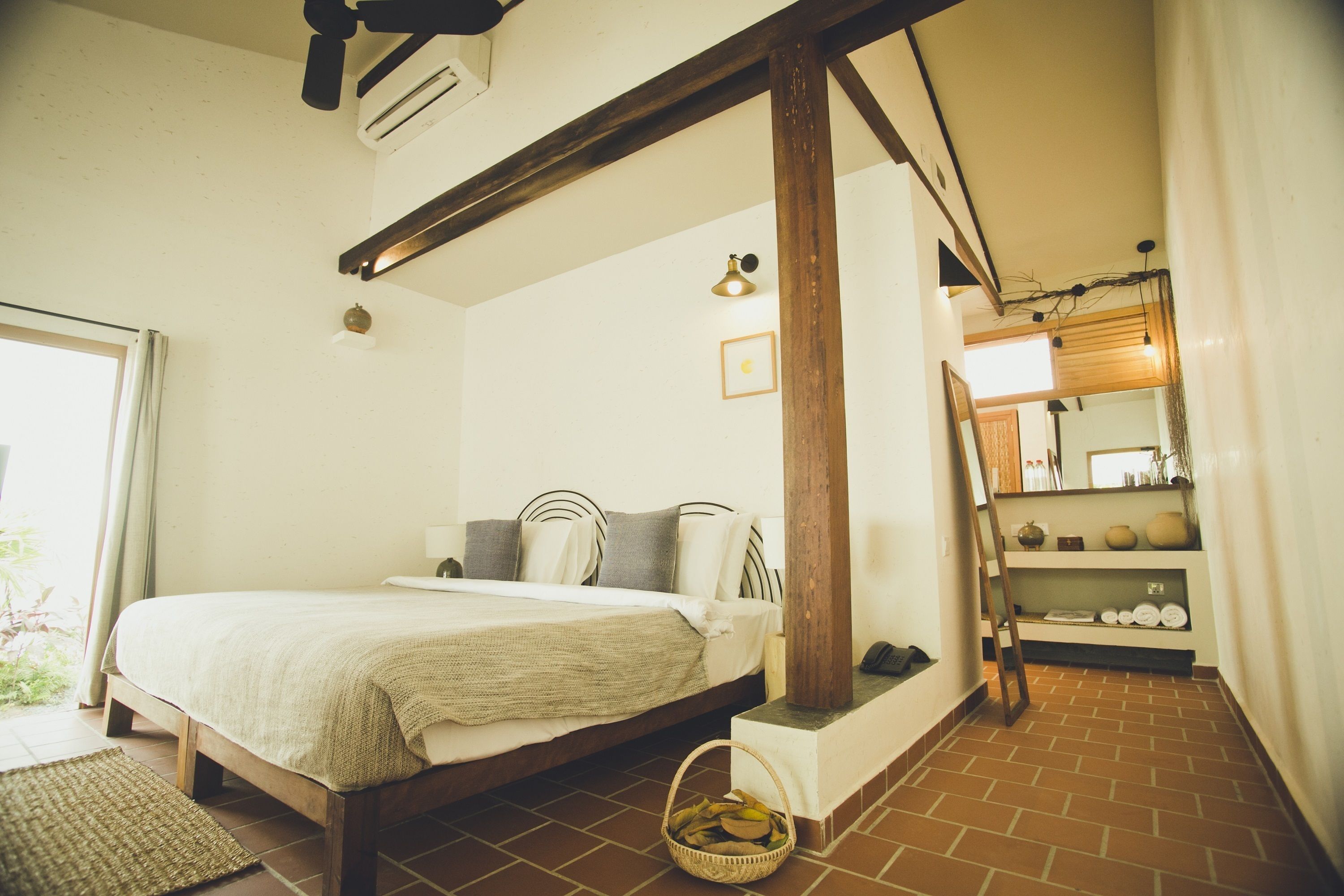 Une chambre à coucher comprenant un lit, une tête de lit en bois, une petite table de chevet, une étagère fixée au mur et une fenêtre avec des rideaux.