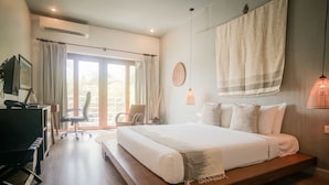 Une chambre moderne avec un grand lit, un bureau avec une chaise et une vue sur l’extérieur grâce à une porte coulissante.