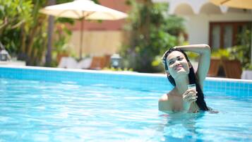 Una piscina con sillones de descanso y sombrillas al fondo.