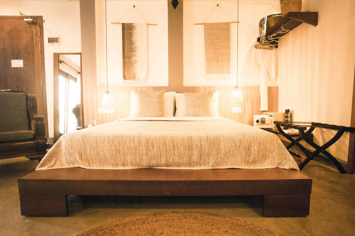 Een groot bed met houten frame en een geribbelde witte spreidek.