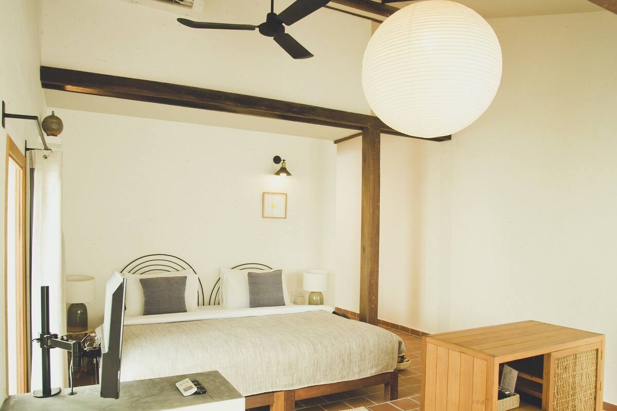 Een slaapkamer met een bed, nachtkastje, lamp en een houten kast.