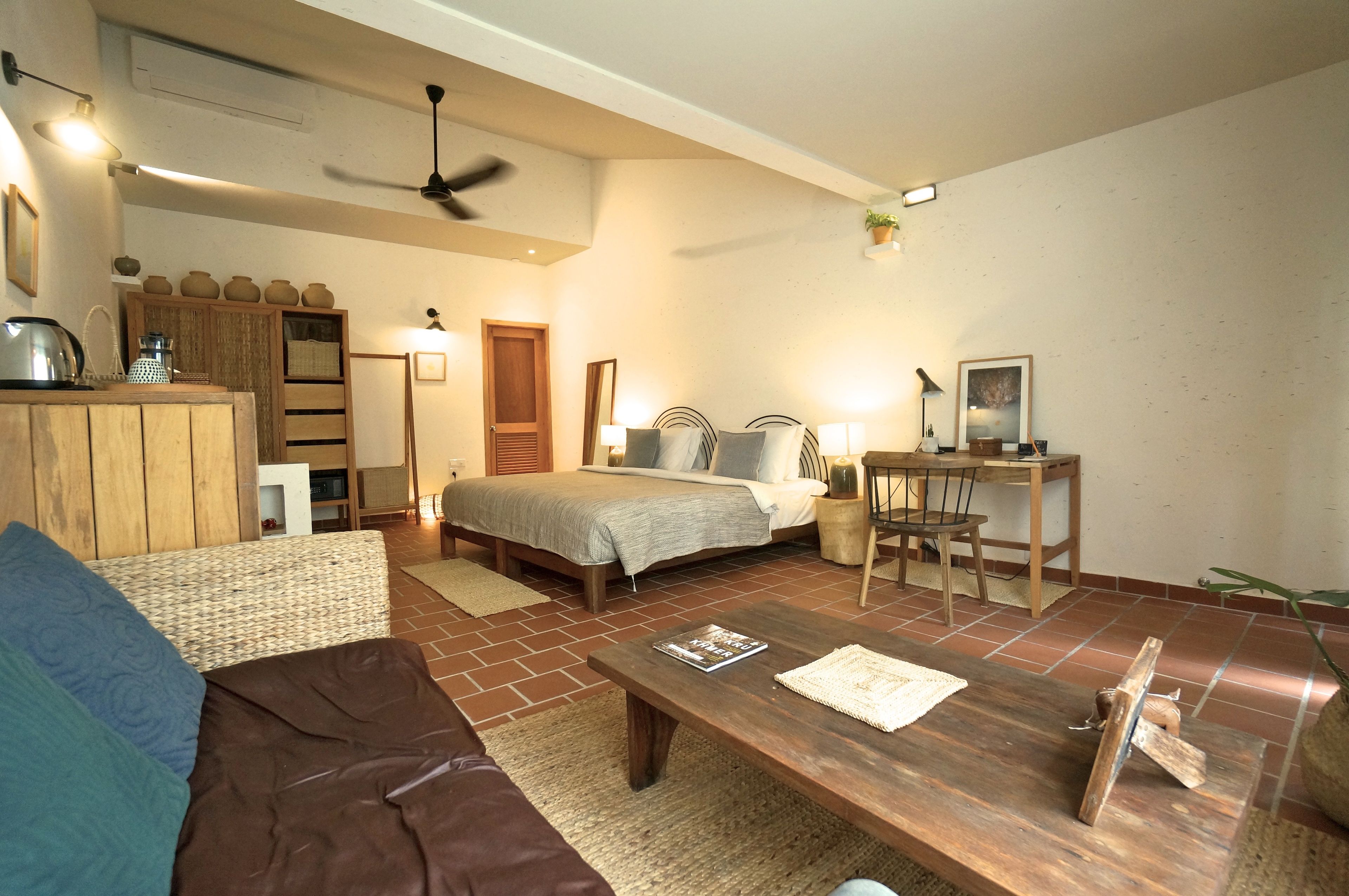 A cozy living room with a bed, a wooden coffee table, and a dining area with a table and chairs.
