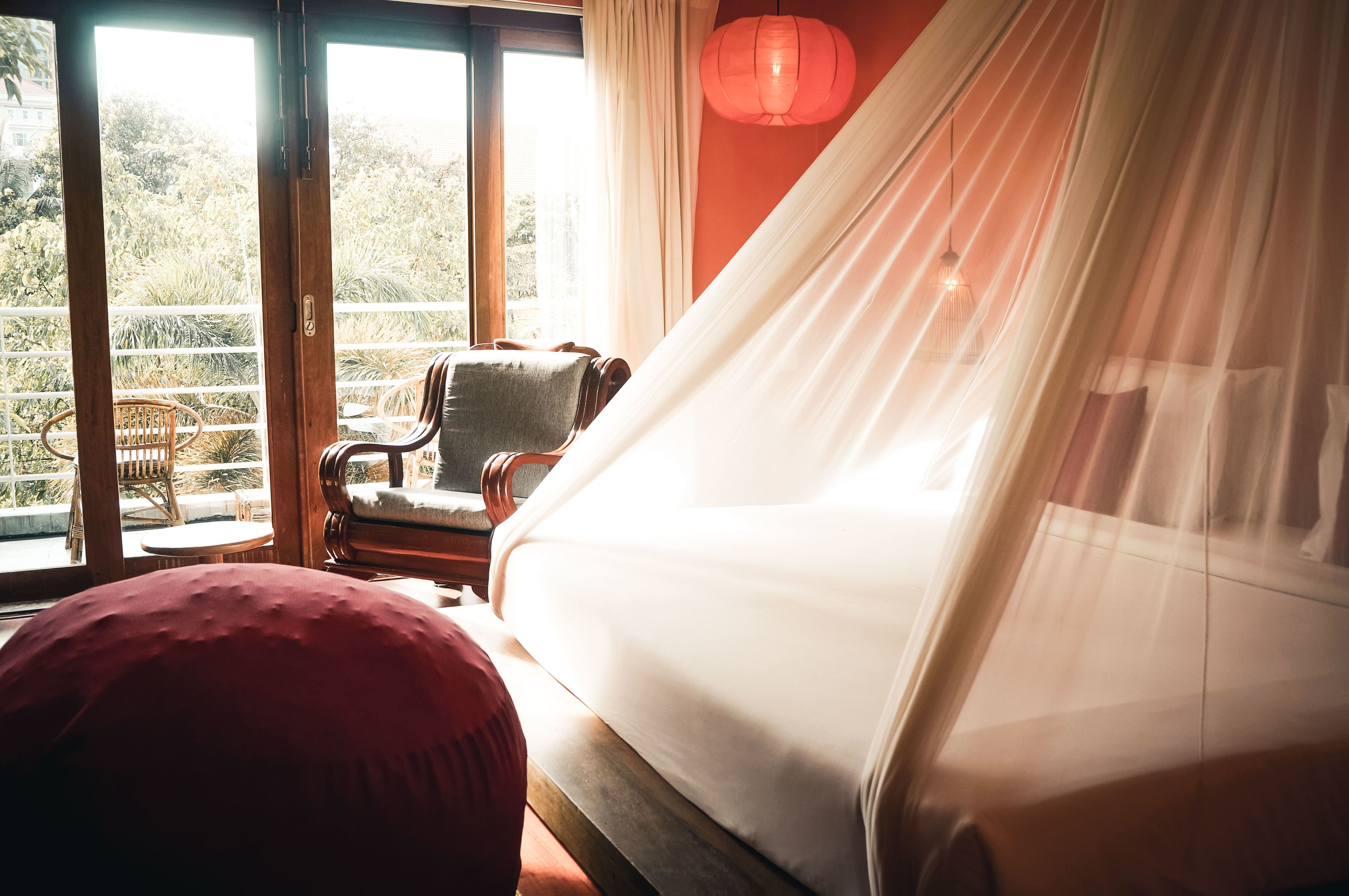A room with a bed, a chair, and a view of greenery outside.