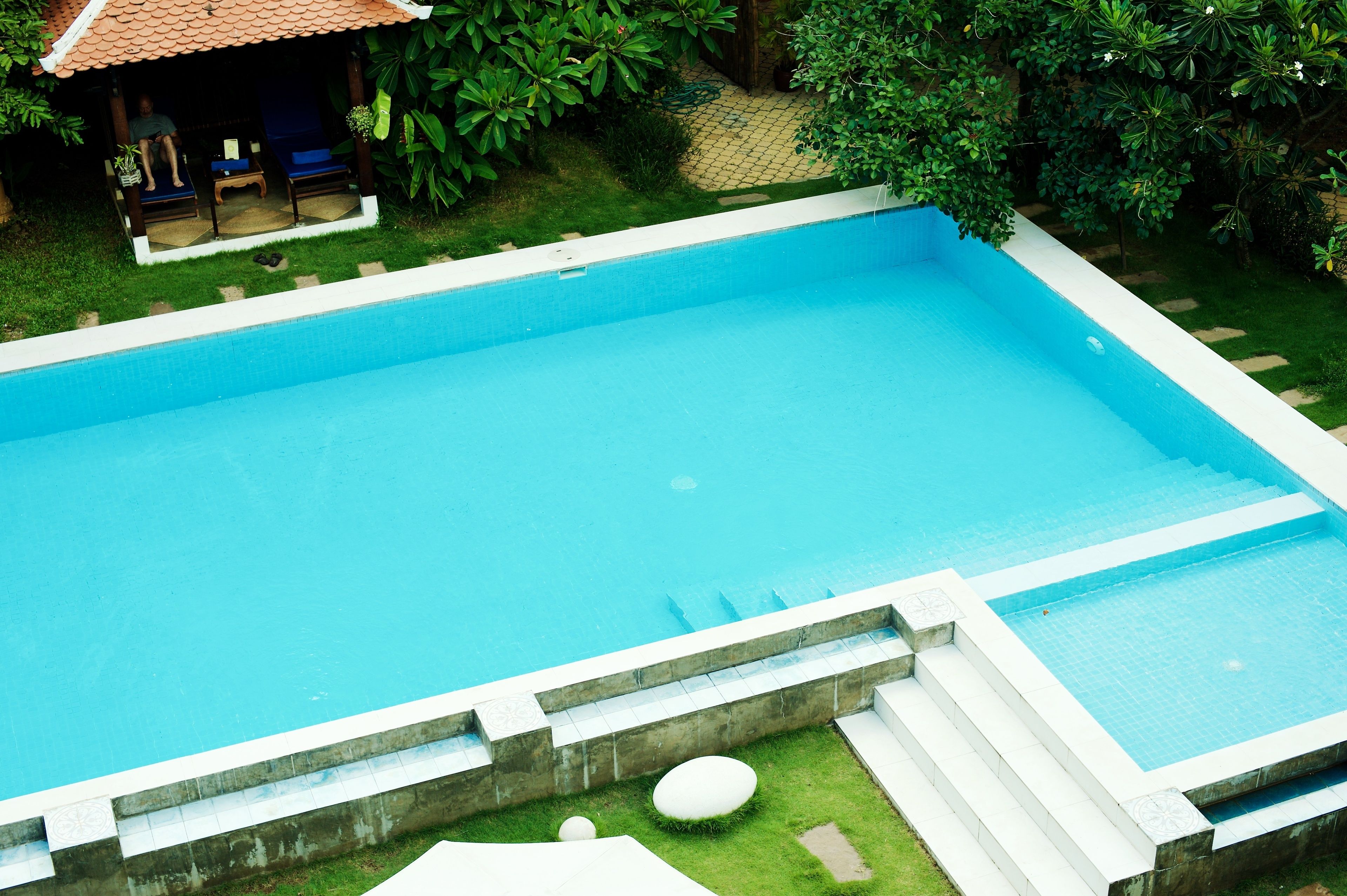 A rectangular swimming pool with a tiled deck and steps leading into the water.