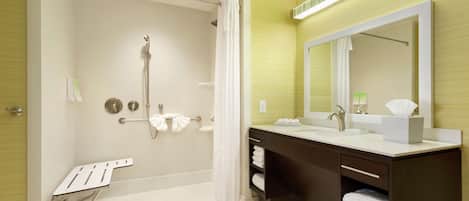 Un baño moderno con ducha, un espejo grande y un tocador con lavamanos.