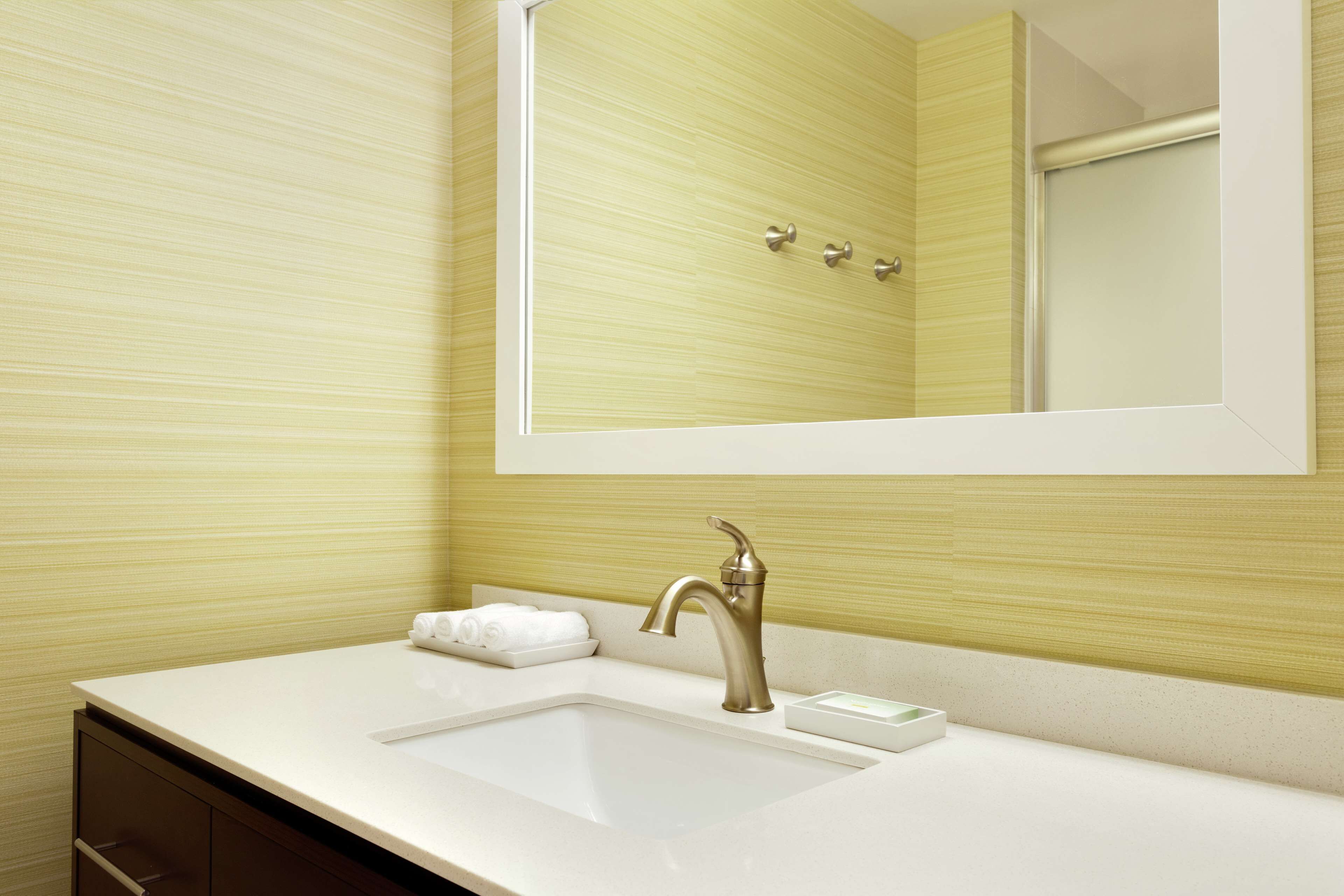 A bathroom with a white sink, a mirror, and a towel rack.