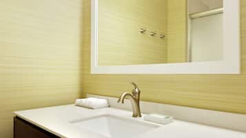 A bathroom with a white sink, a mirror, and a towel rack.