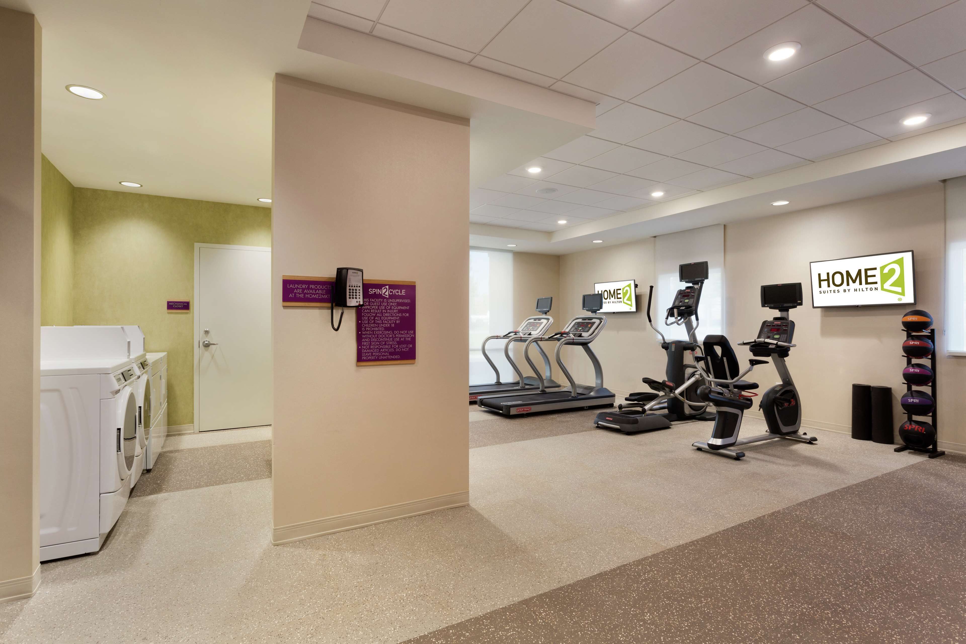 Gimnasio de hotel con cinta de correr, elíptica y máquinas de pesas.