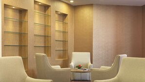 A modern lobby with a wooden wall, glass shelves, and comfortable seating. - Sama-Sama Express KLIA Terminal 2 - Airside Transit Hotel (Sepang)