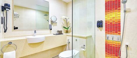 Un baño con cabina de ducha de vidrio, lavamanos, inodoro y espejo.