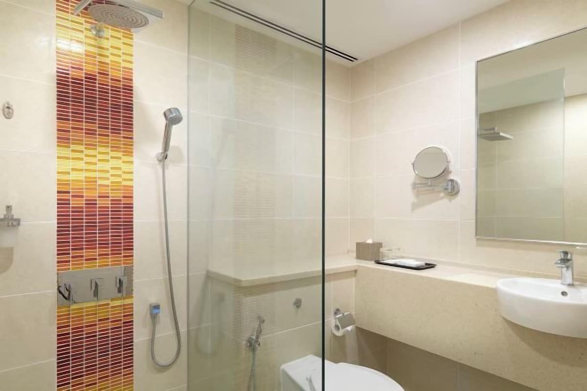 A modern bathroom with a glass shower enclosure, a toilet, a sink, and a mirror.
