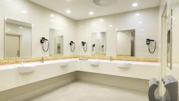 A modern bathroom with three sinks, mirrors, and hair dryers.