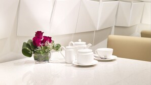 A modern interior with a geometric wall design, a table set with white teacups and a vase of flowers. - Sama-Sama Express KLIA Terminal 2 - Airside Transit Hotel (Sepang)