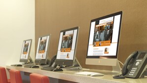 A row of computers with a website displayed on each screen, a telephone, and red chairs in a room with a brown wall. - Sama-Sama Express KLIA Terminal 2 - Airside Transit Hotel (Sepang)