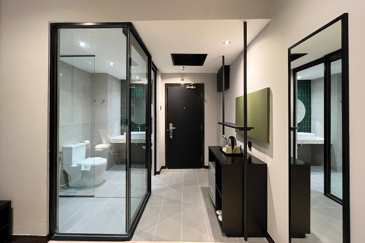 Une salle de bain moderne avec une paroi en verre, des toilettes, un lavabo et un miroir.
