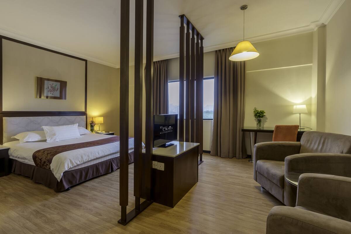 Une chambre d’hôtel avec un lit, un bureau, une chaise et un téléviseur.