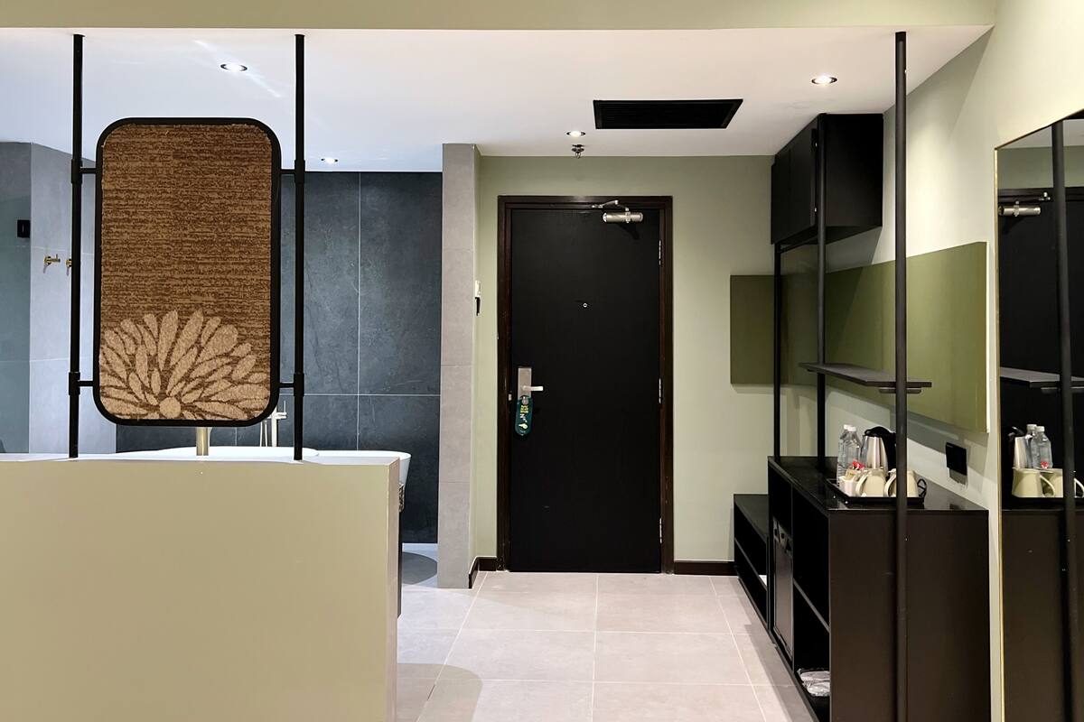 Une salle de bain moderne avec un grand miroir, un porte-serviettes et une porte noire.