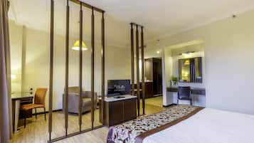 Een hotelkamer met een bed, een bureau met een computer, een stoel, een televisie en een kledingkast.