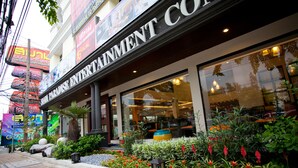 A hotel with a prominent sign, outdoor seating area, and lush landscaping. - Siam Paradise Entertainment Complex (Bangkok)