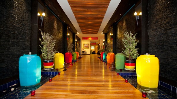 A corridor with a wooden floor and walls, flanked by colorful planters with small trees. - Siam Paradise Entertainment Complex (Bangkok)