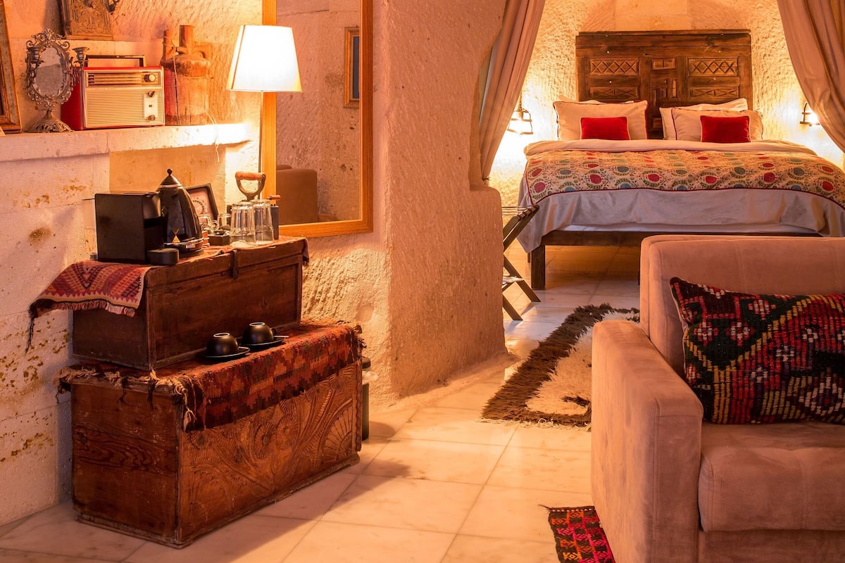 Une chambre à coucher rustique avec un plafond en arc, un lit en bois, une lampe ancienne et une commode.