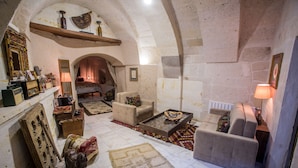 A cozy living room with a fireplace, comfortable seating, and a rustic stone wall.
