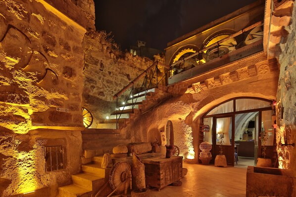 A historic stone building with a staircase leading to an upper level, featuring a large wheel and rustic decor.