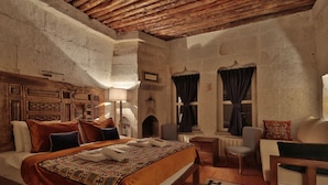 A rustic bedroom with a wooden headboard, a patterned bedspread, a bench, and a chair.