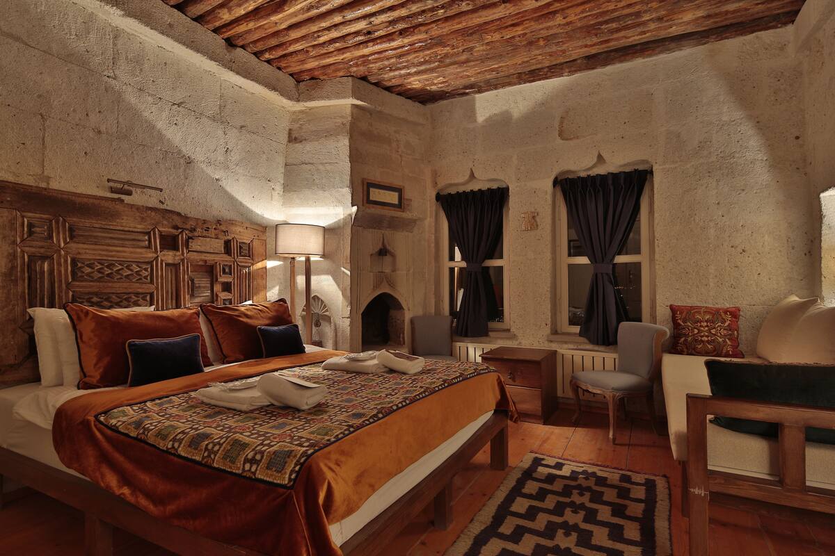 Une chambre à coucher au style rustique, avec une tête de lit en bois, une couvre-lit à motifs, un banc et une chaise.